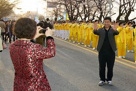 很多游客以法轮功功法演示团为背景拍照留念