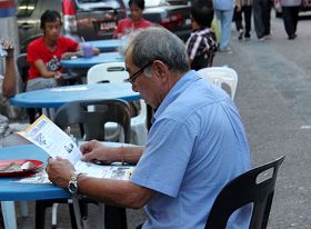 老居民拿到法轮功真相资料后，开始认真地阅读起来。