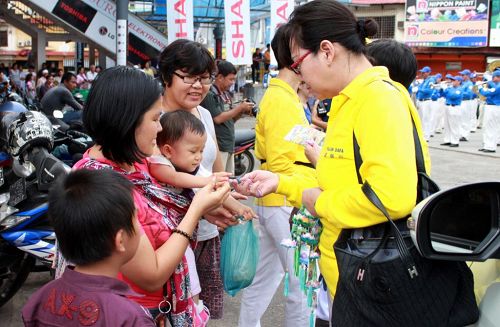 '民众开心的向法轮功学员索取资料和莲花。'