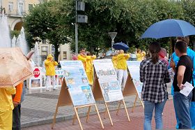 小雨中人们驻足观看展板，了解真相