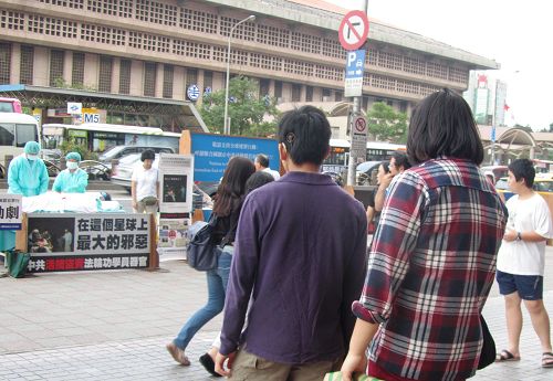 图1.“中共活摘法轮功学员器官”模拟演示剧吸引旅客行人驻足关注。