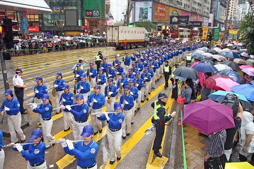 图7-8.由天国乐团引领的法轮功学员的游行，在风雨中照样吸引大批港民及中西游客冒雨观看。