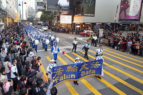 法轮功阵容庞大整齐的游行队伍吸引中西游客及港民驻足观看，纷纷举起相机、手机拍照。