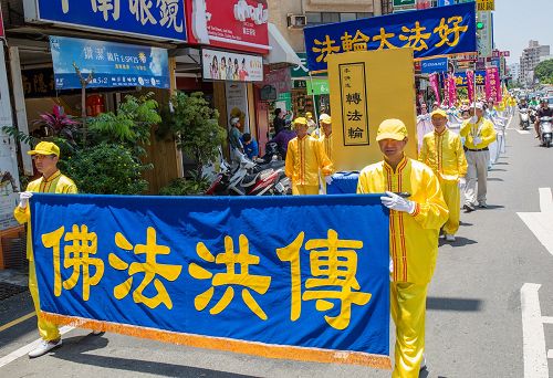 庆祝活动展开《转法轮》巨型模型，学员们精神抖擞举着“法轮大法好”横幅，与民众分享喜悦。