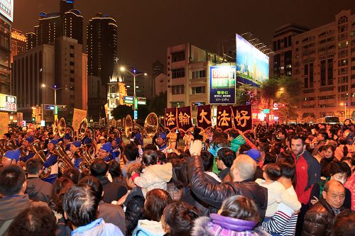 高雄庆元宵游行活动，两侧的观众被天国乐团盛大的阵容震撼，有群众看到法轮功天国乐团队伍来了，就高举双手鼓掌，也有群众高喊“法轮大法好”。