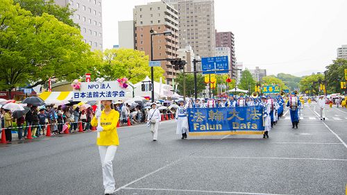 图1-5：法轮功学员参加广岛鲜花节游行——鲜花综合列队表演。游行队伍由气势雄壮的天国乐团、花车、祥和的炼功队等组成，宛如明珠剔透秀于群芳，光彩夺目。