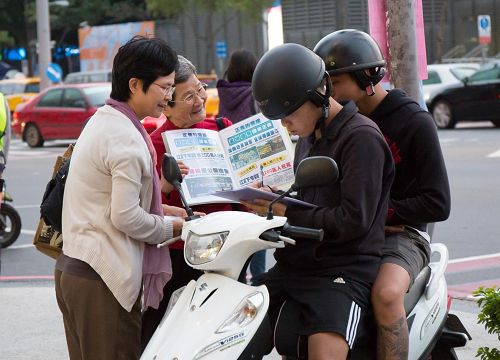 '图2：洵姨（左二）每天到景点发传单、举真相展板，让游客明白“法轮大法好”。'