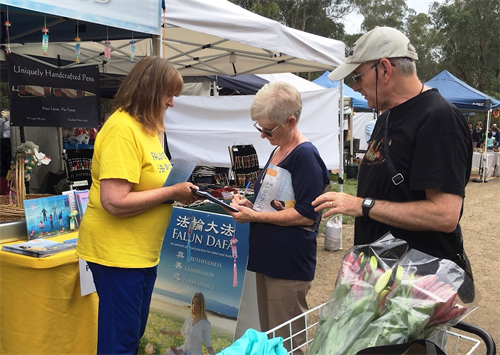 '图4：十二月十五日，亚拉河畔沃伦戴特（Warrandyte）区的圣诞市集上，得知真相的人们在制止迫害的征签表上签名。'