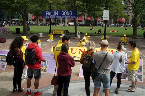 '图3：波士顿市科普利广场上，民众驻足观看法轮功学员炼功'