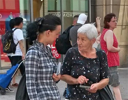 '图10:这位老年女士(右)拿着介绍法轮功和揭露中共迫害的传单,询问学员(左)有关法轮功的真相。'