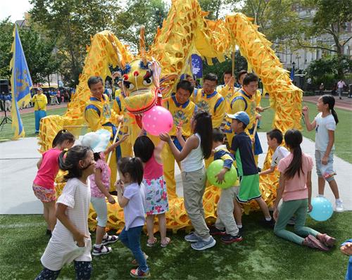 '图2：迎中秋，法轮功学员给纽约华埠民众送祝福。小朋友们特别喜欢精彩的舞龙表演。'