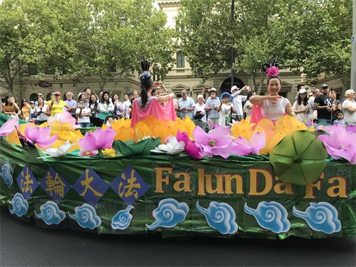 用莲花和祥云装饰的花船上，仙女妆扮的学员们演示法轮功功法。