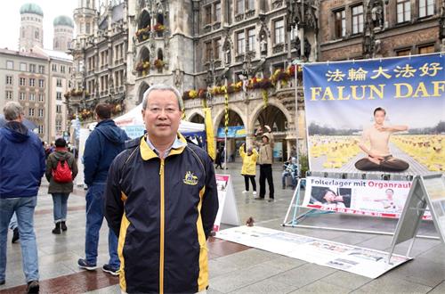 '图7：前北大经济学教授夏业良在慕尼黑玛琳广场两次遇到法轮功学员举办活动。图为十月七日夏教授在慕尼黑玛琳广场。'