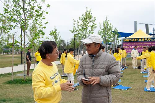 '图3：法轮功学员在向越南裔居民楚先生（Loc Chu）在向民众介绍法轮功功法。'