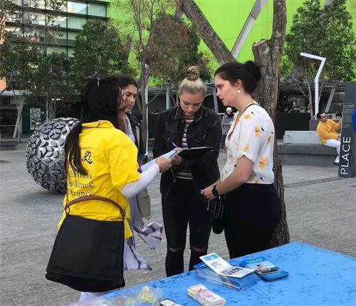 '图6：澳洲西人女孩子奥利维亚（Olivia，右二）在征签簿上签字，呼吁制止中共对法轮功的迫害'