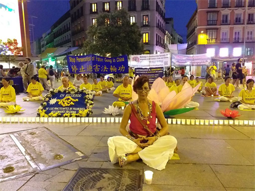 '图3：2019年7月19日，在马德里Callao广场，Vivian Acosta女士和法轮功学员一起，席地而坐，烛光守夜。'
