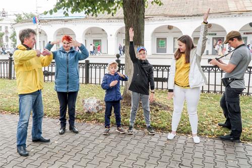 '图10～11：法轮功学员在市政府对面的巴特尼科夫（Botnikovsky）中心花园展示功法，观众现场学炼法轮功。'