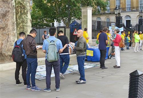 '图7：一群大陆年轻人在跟法轮功学员交谈并观看展板和资料，图为唐宁街十号首相府对面。'