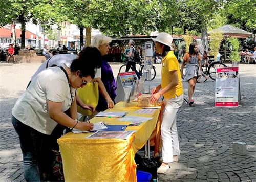 '图4～5：法轮功学员在慕尼黑居民区红十字广场（Rotkreuzplatz）举办讲真相活动'