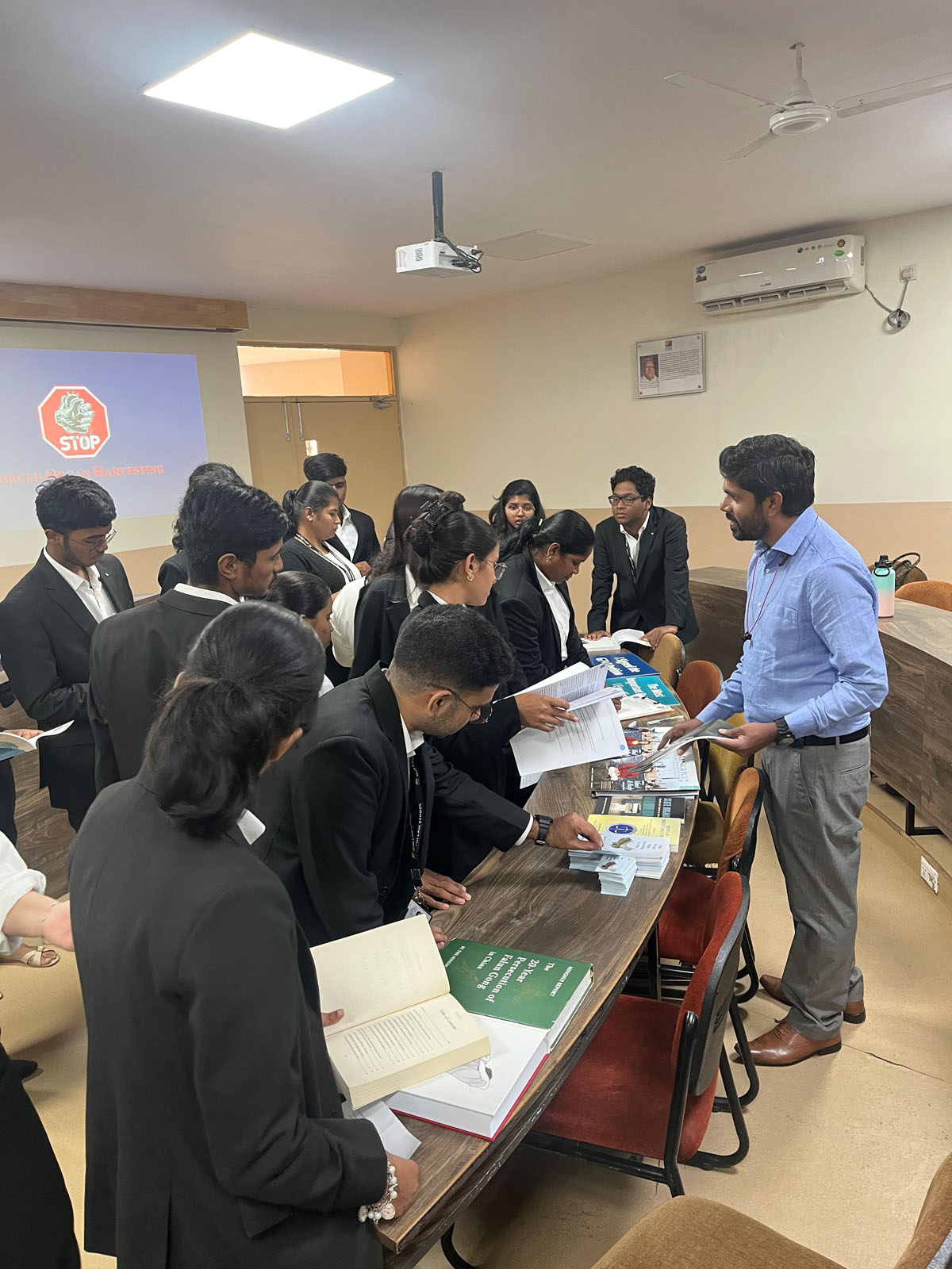 图2:一位法轮大法学员正在与学生们交谈,他们在翻阅《明慧》特刊和《魔鬼在统治着我们的世界》一书。