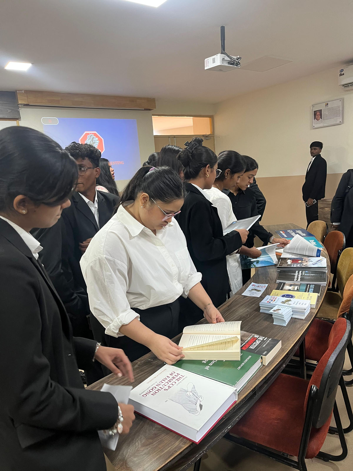 图6:姆里纳利尼与朋友们在翻阅有关法轮大法遭受迫害及中共活摘器官的报告与书籍。