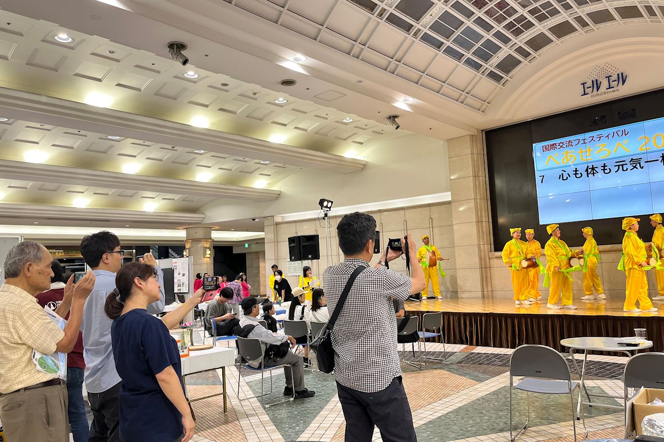 '图3:观看法轮功学员舞台表演的观众专注地用手机拍摄。'