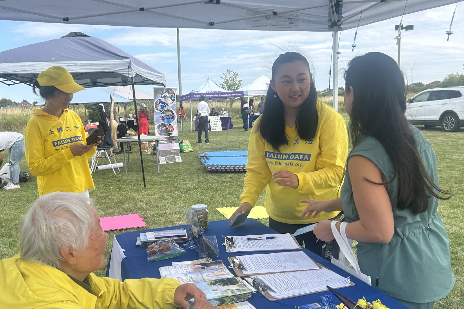 图7: 在法轮功展位前,各族裔的加拿大人纷纷在请愿信上签名,呼吁加拿大国会立法制止中共跨国镇压。